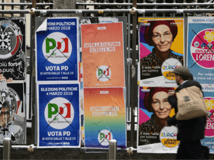A pedestrian passes in front of election hoardings in Milan on March 1, 2018, prior to the Italian presidential elections. Growth up, deficit down: Italian Prime Minister Paolo Gentiloni's centre-left government got a boost from new data ahead of a weekend election in which the state of the economy is …
