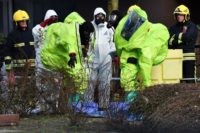 BRITAIN-RUSSIA-POLICE-ESPIONAGE Members of the fire brigade are helped out of their green biohazard suits by colleagues in white protective coveralls after an operation to re-attach the tent over the bench where a man and a woman were found in critical condition sparking a major incident on March 4 at The Maltings …