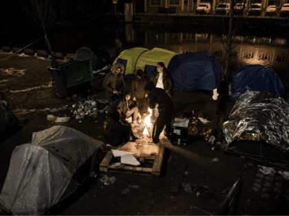 Migrants, mostly from Afghanistan, warm themselves up around a bonfire in freezing tempera