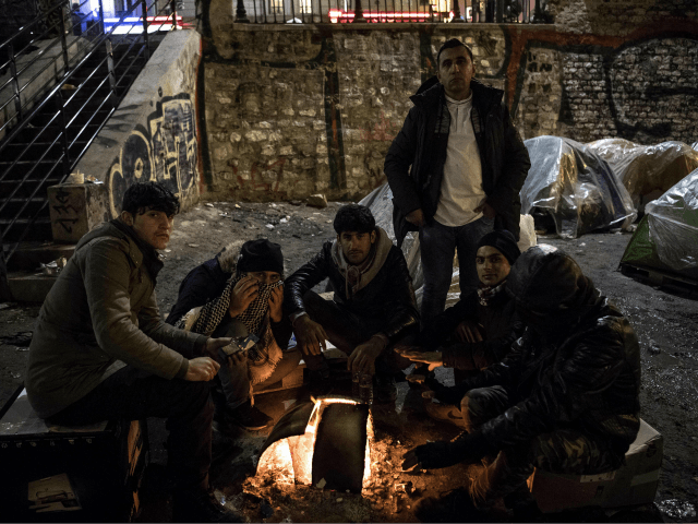 Migrants, mostly from Afghanistan, warm themselves up around a bonfire in freezing temperatures, by their tents at a makeshift camp set up along the canal Saint-Martin in Paris on March 19, 2018. / AFP PHOTO / CHRISTOPHE ARCHAMBAULT (Photo credit should read CHRISTOPHE ARCHAMBAULT/AFP/Getty Images)