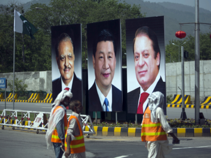 In this April 20, 2015 file photo, municipality workers walk past a billboard showing pictures of Chinese President Xi Jinping, center, with Pakistan's President Mamnoon Hussain, left, and Prime Minister Nawaz Sharif on display during a two-day visit by the Chinese president to launch an ambitious $45 billion economic corridor …