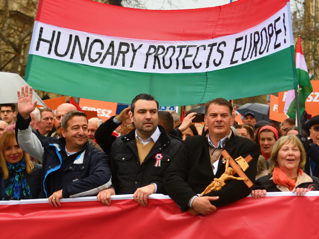 Demonstrators hold a flag in the colors of Hungary reading 'Hungary protects Europe' as they arrive to listen to a speech of their Prime Minister in Budapest on March 15, 2018, as celebrations are under way to commemorates the 170th anniversary of the 1848-1849 Hungarian revolution and independence war on …