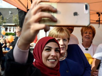 A syrian refugee (L) poses for a selfie photo with German Chancellor Angela Merkel (C) as