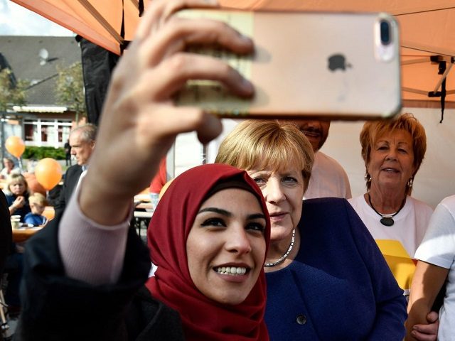A syrian refugee (L) poses for a selfie photo with German Chancellor Angela Merkel (C) as she continued on the election campaign trail in Stralsund on September 16, 2017, a week before Germans head to the polls. / AFP PHOTO / John MACDOUGALL / ALTERNATIVE CROP (Photo credit should read …