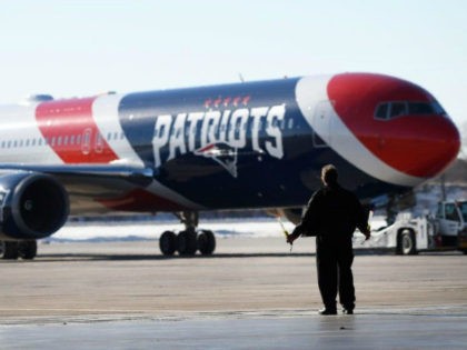 A member of the ground crew guides the team plane of the New England Patriots as it arrive