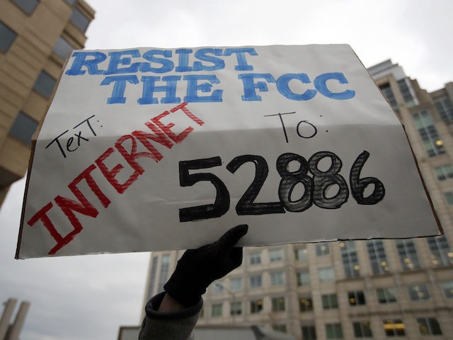 A protester holds a sign that reads "Resist the FCC Text: INTERNET To: 52886" at the Federal Communications Commission (FCC), in Washington, Thursday, Dec. 14, 2017. The FCC voted to eliminate net-neutrality protections for the internet. (AP Photo/Carolyn Kaster)