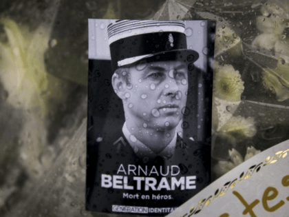 A photo of Lieutenant Colonel Arnaud Beltrame placed on a bunch of flowers at the main gate of the Police headquarters in Carcassonne, France, Saturday, March 24, 2018, following an attack on a supermarket in Trebes in the south of the country on Friday. A French police officer who offered …