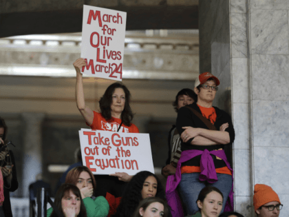 An attendee at a rally against gun violence holds signs that read "March for Our Lives March 24" and "Take Guns Out of the Equation," Tuesday, March 6, 2018, at the Capitol in Olympia, Wash. The rally was held on the same day Gov. Inslee was scheduled to sign a …