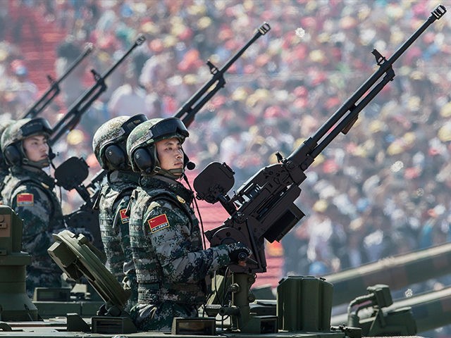 BEIJING, CHINA - SEPTEMBER 03: Chinese soldiers ride in an armoured vehicle as they hold machine guns while passing in front of Tiananmen Square and the Forbidden City during a military parade on September 3, 2015 in Beijing, China. China is marking the 70th anniversary of the end of World …