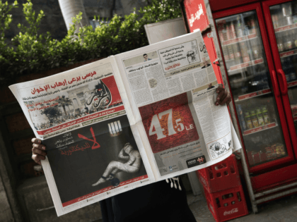 A woman reads a copy of Egyptian newspaper 'Al-Tahrir' with the headline 'No to Dictatorship' on December 3, 2012 in Cairo. A cartoon of a newspaper in human form chained in a cell was pasted on the front of several independent papers including Al-Watan and Al-Masry Al-Youm with the line …