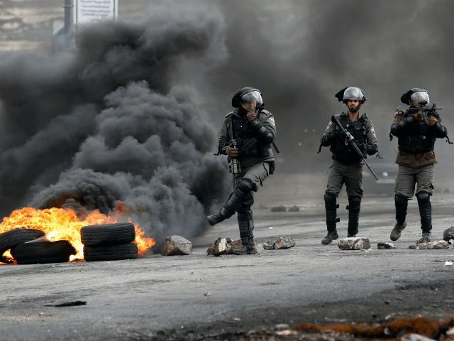 Israeli border guards walk through fumes from burning tires during clashes with Palestinian protesters near the Israeli settlement of Beit El in the Israeli occupied West Bank, on March 30, 2018, after Land Day demonstrations. Land Day marks the killing of six Arab Israelis during 1976 demonstrations against Israeli confiscations …
