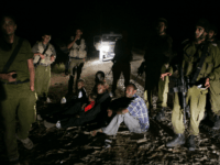 In this Aug. 20, 2007 file photo, a Sudanese refugee family sit on the ground surrounded by Israeli army soldiers after they crossed illegally from Egypt into Israel. The Israeli Cabinet voted unanimously Sunday, Dec. 11, 2011, to finance a $160 million program designed to staunch the flow of illegal African migrants into Israel by stepping up construction of a border fence and expanding a detention center to hold thousands of the new arrivals. (AP Photo/Ariel Schalit, File)