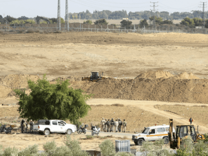 Hamas security forces secure the area while Palestinian bulldozers, at foreground, and Isr
