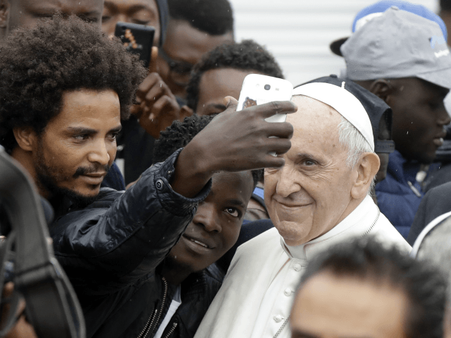In this Oct. 1, 2017 file photo, Pope Francis poses for selfies with migrants at a regional migrant center, in Bologna, Italy. In a message issued by the Vatican Friday, Nov. 24, 2017, Francis is decrying those whipping up fear of migrants for political gain, and is urging people to ...