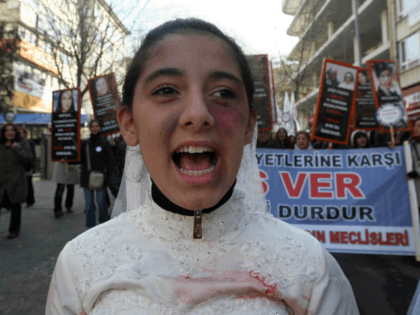 A Turkish girl, wearing a wedding dress and covered with fake bruises, shouts in front of other protesters holding placard reading '' end violence'' during a demonstration to protest against rape, killings and domestic violence against women, in Ankara on November 27, 2011. AFP PHOTO/ADEM ALTAN (Photo credit should read …