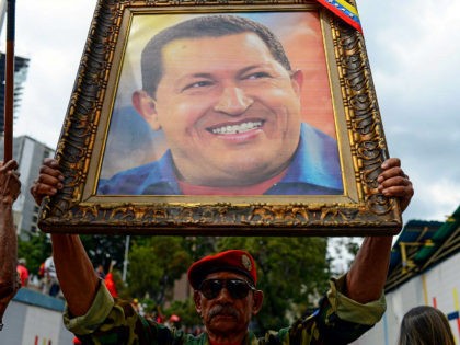 A soldier holds a portrait of late Venezuelan President Hugo Chavez during a rally to comm