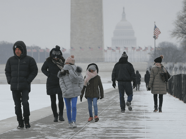 People are seen walking alongside the reflecting pool on the National Mall in Washington, Thursday, Jan. 4, 2018. Residents across a huge swath of the U.S. have awakened to the beginnings of a massive winter storm expected to deliver snow, ice and high winds followed by possible record-breaking cold as …