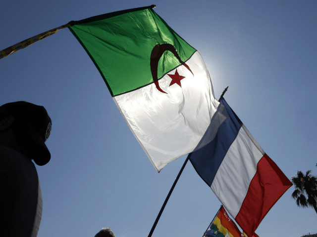 People wave the French and Algerian flags during a demonstration against a municipal order