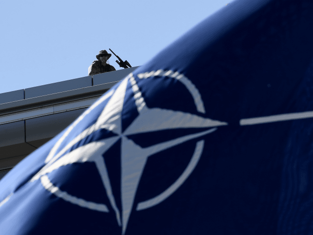 A military personnel stands guard on top of the roof during the NATO (North Atlantic Treat