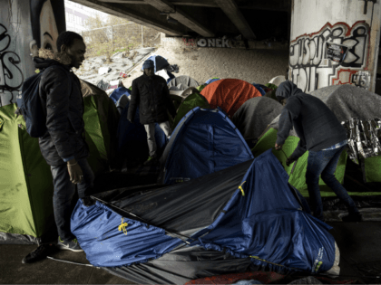 Migrants set up a tent at a makeshift camp set under a bridge along the canal de Saint-Den