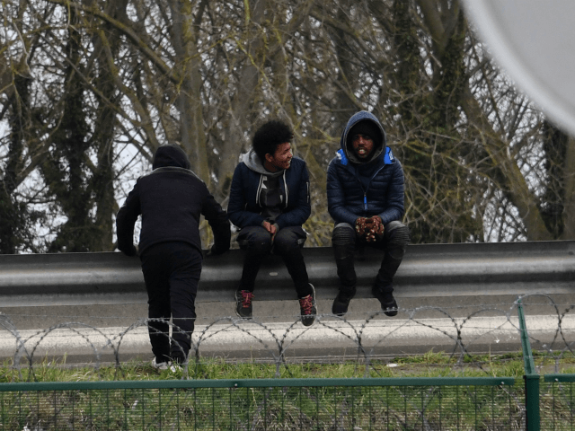 Migrants sit on a crash barrier by the ringroad leading to the harbour on March 30, 2018 in Calais. / AFP PHOTO / Denis Charlet (Photo credit should read DENIS CHARLET/AFP/Getty Images)