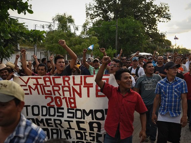 Central American migrants taking part in a caravan called "Migrant Viacrucis" towards the United States raise their fists and hold a banner reading "Emigrant Viacrucis 2018. We are all America. No to discrimination" as they march to protest against US President Donald Trump's policies in Matias Romero, Oaxaca State, Mexico, …