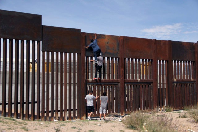 A young Mexican helps a compatriot to climb the metal wall that divides the border between Mexico and the United States to cross illegally to Sunland Park, from Ciudad Juarez, Chihuahua state, Mexico on April 6, 2018. US President Donald Trump on April 5, 2018 said he would send thousands …