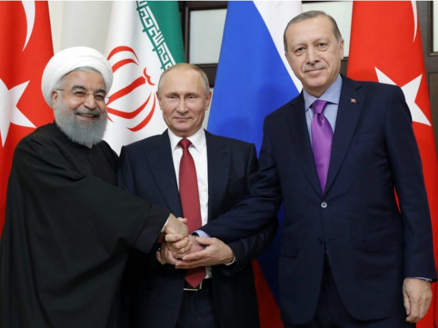 Russian President Vladimir Putin flanked by Turkish President Recep Tayyip Erdogan (r) and Iranian President Hassan Rouhani pose during a trilateral meeting on Syria in Sochi last November