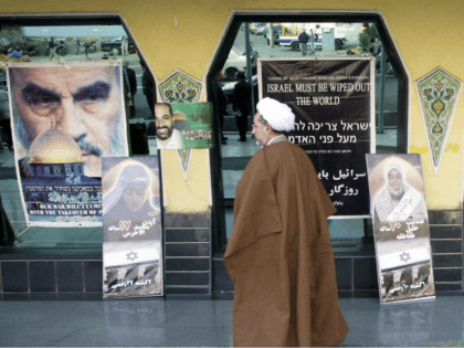 An Iranian clergyman passes anti-Israeli posters, during activities marking the 10th anniv