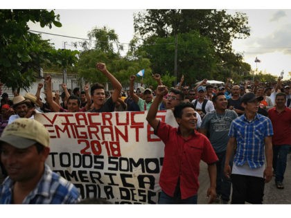 Central American migrants taking part in a caravan called 'Migrant Viacrucis' towards the United States raise their fists and hold a banner reading 'Emigrant Viacrucis 2018. We are all America. No to discrimination' as they march to protest against US President Donald Trump's policies in Matias Romero, Oaxaca State, Mexico, …