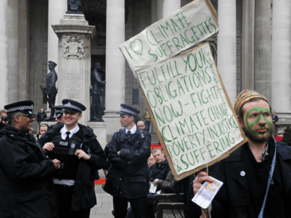 British policemen (L) share a joke as a man protests against Climate Change, Poverty and Injustice and Suffering, outide the Royal Exchange in London, on March 31, 2009. London is bracing for angry protests before and during Thursday's G20 summit, which will see fortress-like security for world leaders including US …
