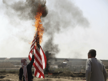 Palestinian protesters burn an American flag during a protest at the Gaza Strip's border with Israel, Friday, April 6, 2018.