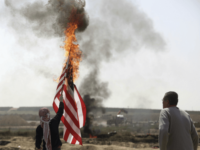 Palestinian protesters burn an American flag during a protest at the Gaza Strip's border w