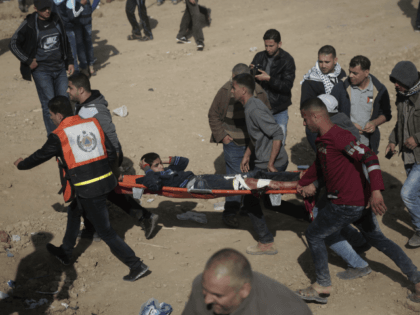 Palestinian protesters carry a wounded youth who was shot by Israeli troops during a demonstration near the Gaza Strip border with Israel, in eastern Gaza City, Friday, March 30, 2018. (AP Photo/ Khalil Hamra)