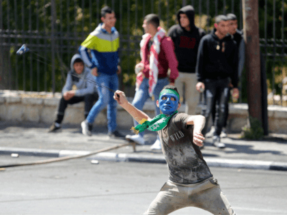 A Palestinian protester hurls stones towards Israeli border police officers during clashes in the West Bank city of Bethlehem, Saturday, March 31, 2018. Israel's chief military spokesman says if violence drags on along the Gaza border, Israel will expand its reaction to strike the militants behind it. (AP Photo/Nasser Shiyoukhi)