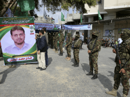 Relatives sit up a photo while masked militants from the Izzedine al-Qassam Brigades, a mi
