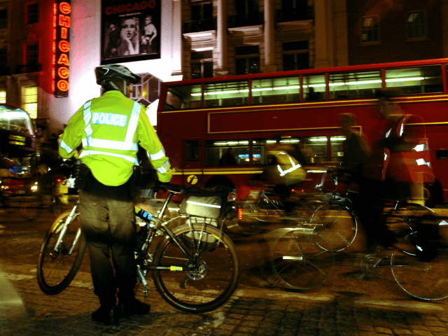 An officer of the Metropolitan Police on bicycle watches approximately 200 cyclist sympathisers of the Critical Mass cyclists`group make their way from the South Bank and along the Strand past the theatre district, 28 October 2005 in London, United Kingdom. Critical Mass, who have made the same journey every month …