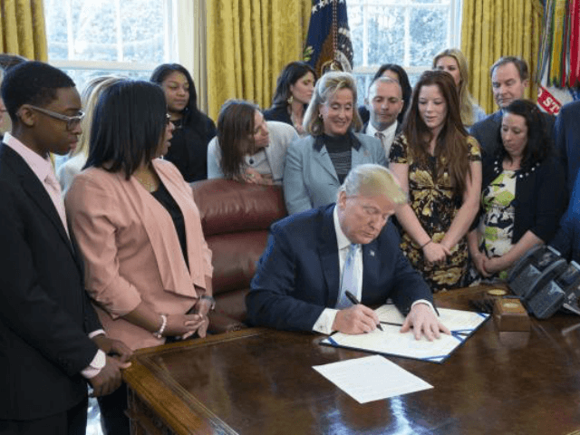 President Donald.Trump signs a law Wednesday aimed at targeting sex trafficking online. He is surrounded by victims and lawmakers who helped pass the bill. Photo by Chris Kleponis/UPI