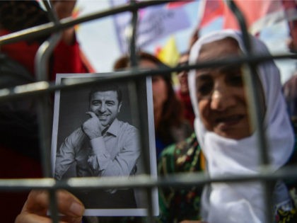 A woman standing behind a fence holds a portrait of Selahattin Demirtas, a jailed former l