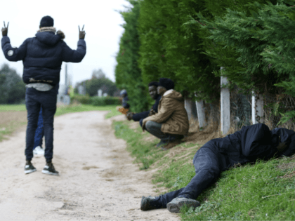 Sudanese migrants wait or sleep on the side of a road in Ouistreham, near Caen, northweste