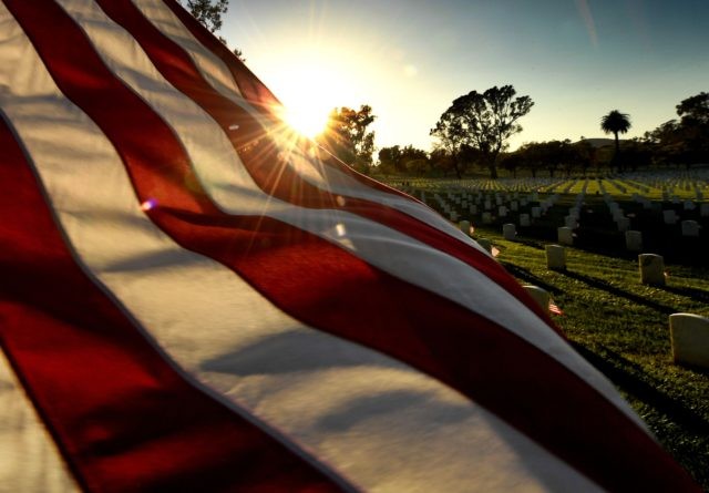 TOPSHOT - The sun sets over a flag at the Los Angeles National Military Cemetery two days before Memorial Day in Los Angeles, California on May 26, 2018. - Memorial Day, which originated after the US Civil War that ended in 1865, is an American holiday honoring the men and …
