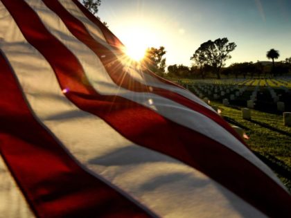 TOPSHOT - The sun sets over a flag at the Los Angeles National Military Cemetery two days before Memorial Day in Los Angeles, California on May 26, 2018. - Memorial Day, which originated after the US Civil War that ended in 1865, is an American holiday honoring the men and …