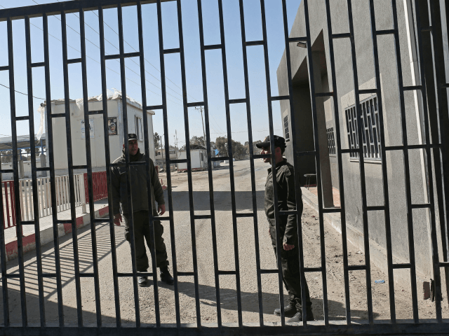 Palestinian security forces loyal to the Palestinian Authority (L) stand at the gate of the Kerem Shalom crossing, the main passage point for goods entering Gaza, after is was closed by Israel following the discovery of tunnels underneath the crossing, in the southern Gaza Strip town of Rafat on January …