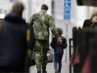 A soldier and a boy walk away after they offered flowers near the department store Ahlens following a suspected terror attack in central Stockholm, Sweden, Saturday, April 8, 2017.
