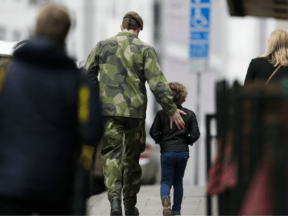 A soldier and a boy walk away after they offered flowers near the department store Ahlens