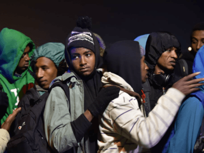 Migrants queue for transportation by bus to reception centres across France, from the &#03