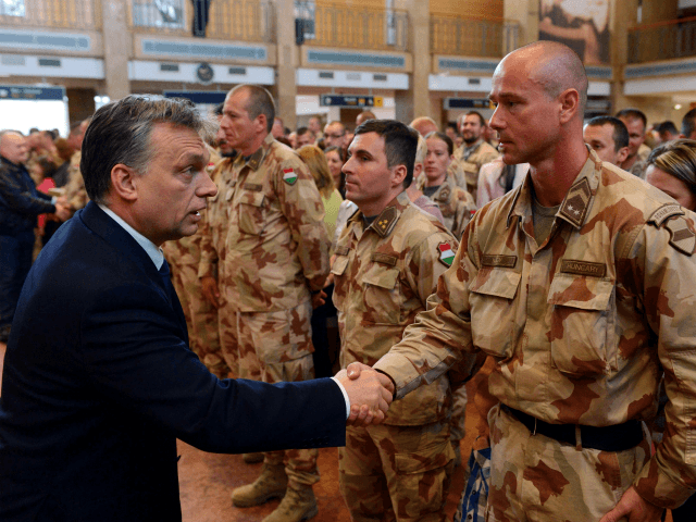 Hungarian Prime Minister Viktor Orban, left, welcomes Hungarian army soldiers as the last