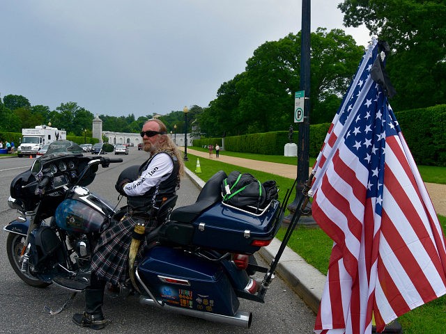 A biker wearing a kilt with three American flags on his Harley Davidson arrives at Arlington National Cemetery on Sunday. (Penny Starr/Breitbart News)