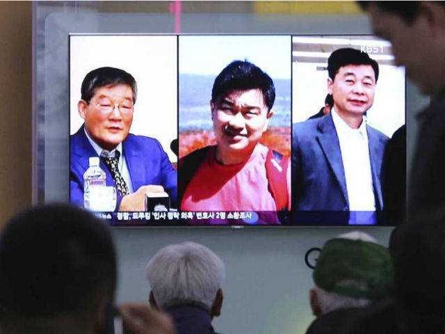 In this May 3, 2018, photo, people watch a TV news report on screen showing portraits of t