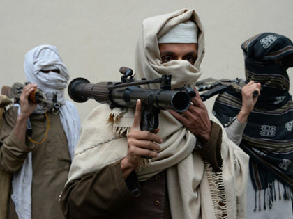 Former Afghan Taliban fighters carry their weapons before handing them over as part of a g